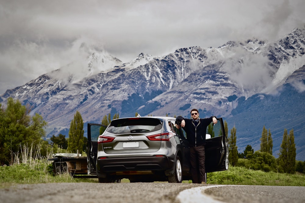 man in black jacket standing beside white chevrolet car