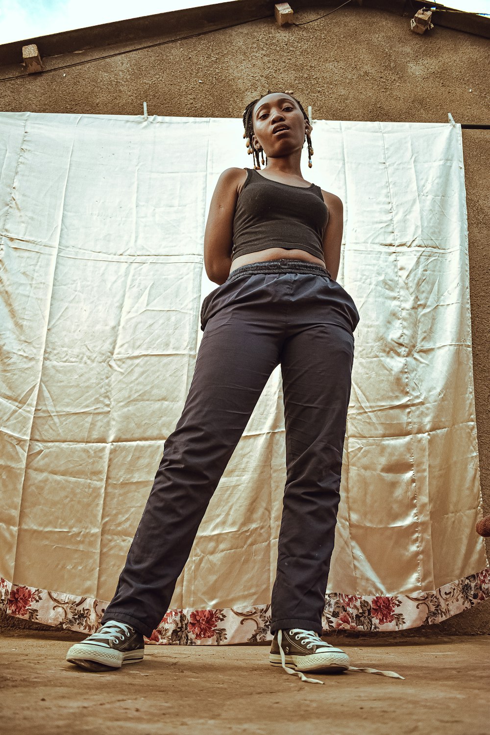 woman in gray tank top and blue denim jeans standing beside white wall