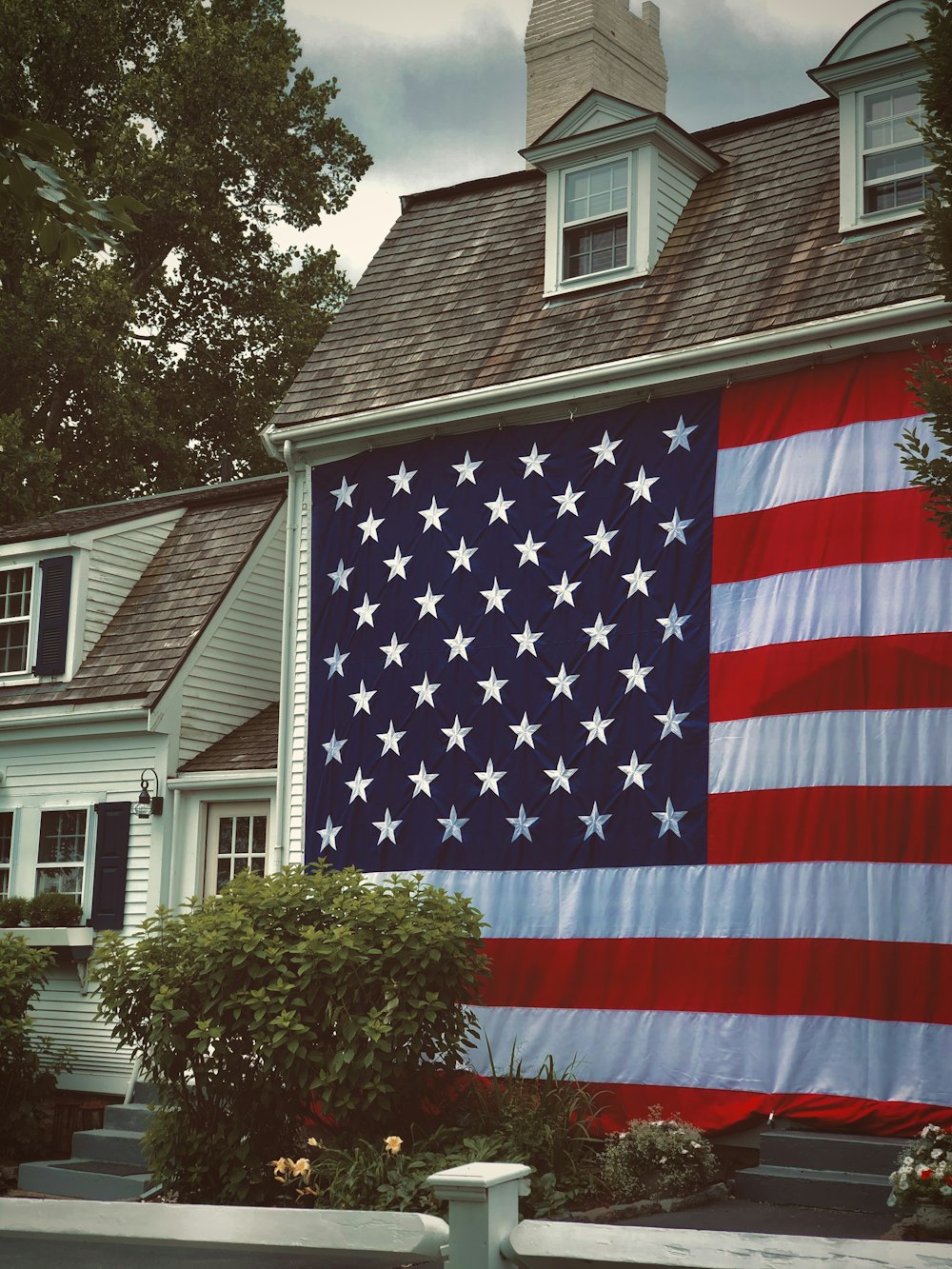 us a flag on pole near green tree during daytime