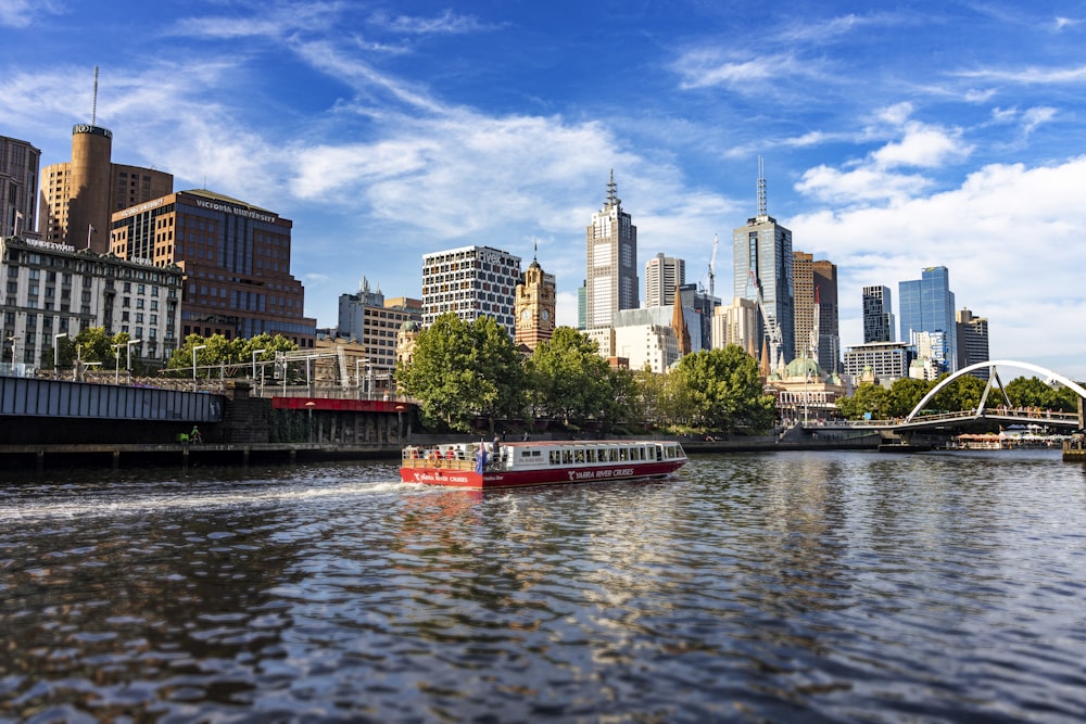 red and white boat on river near city buildings during daytime