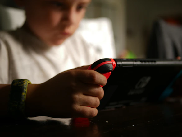 Tyler Lagalo (Unsplash) boy in white crew neck t-shirt holding black and red cordless device