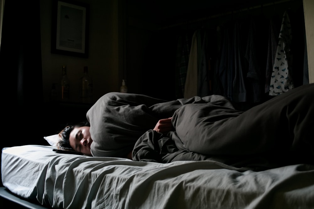 man in black jacket lying on bed