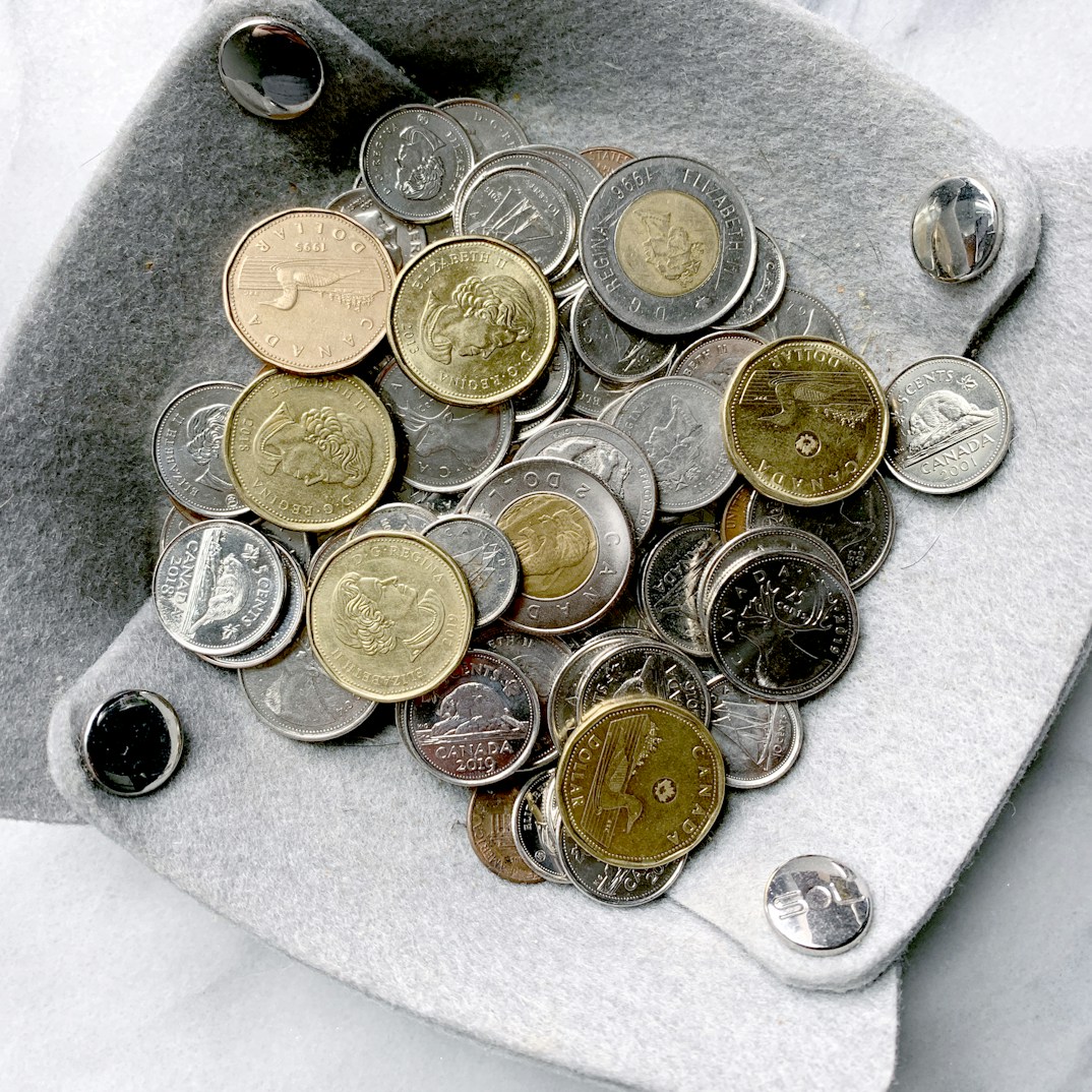 gold and silver round coins on gray surface by Ilana Gotz (@ilanagotz)