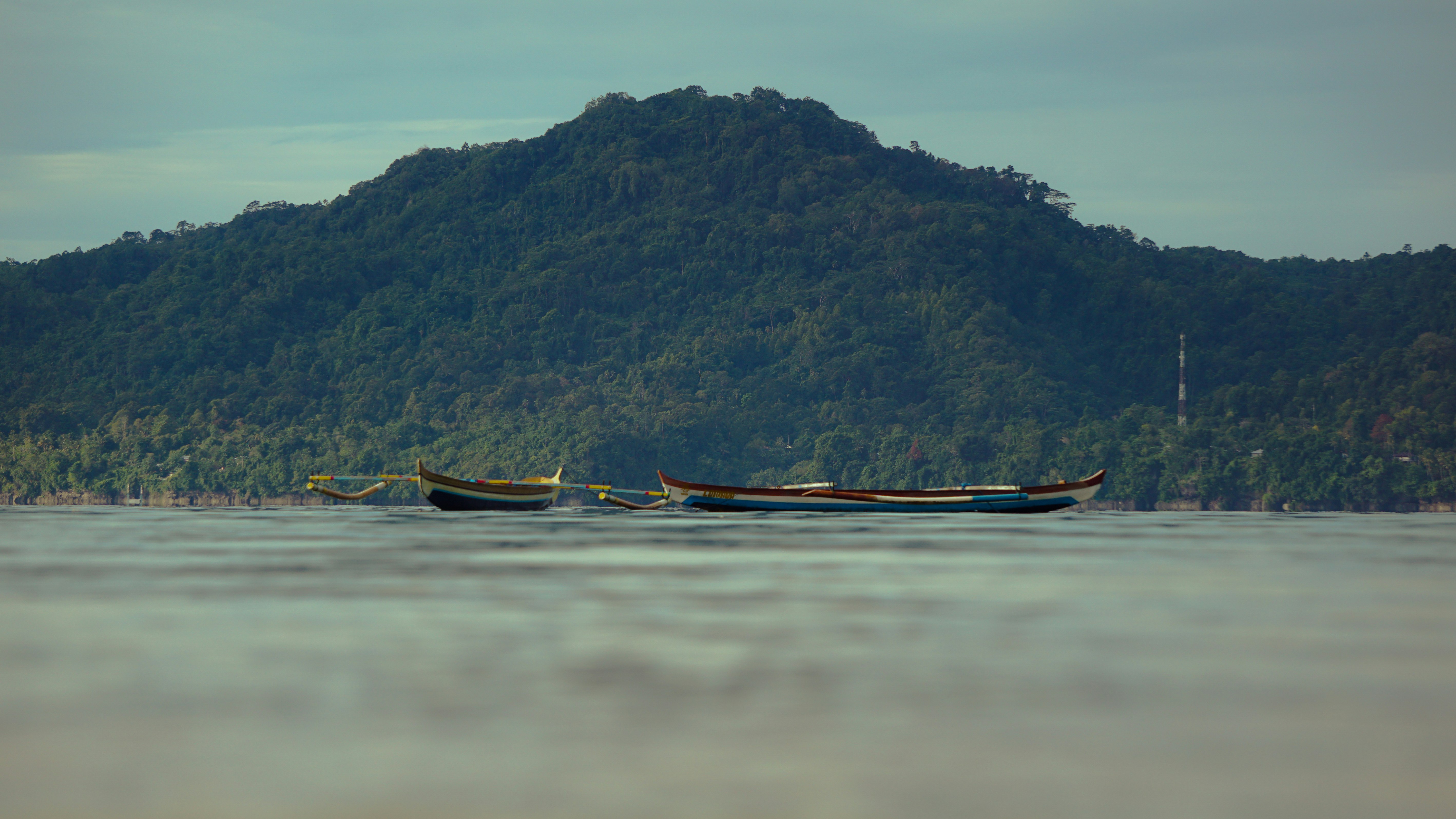 brown boat on body of water near mountain during daytime