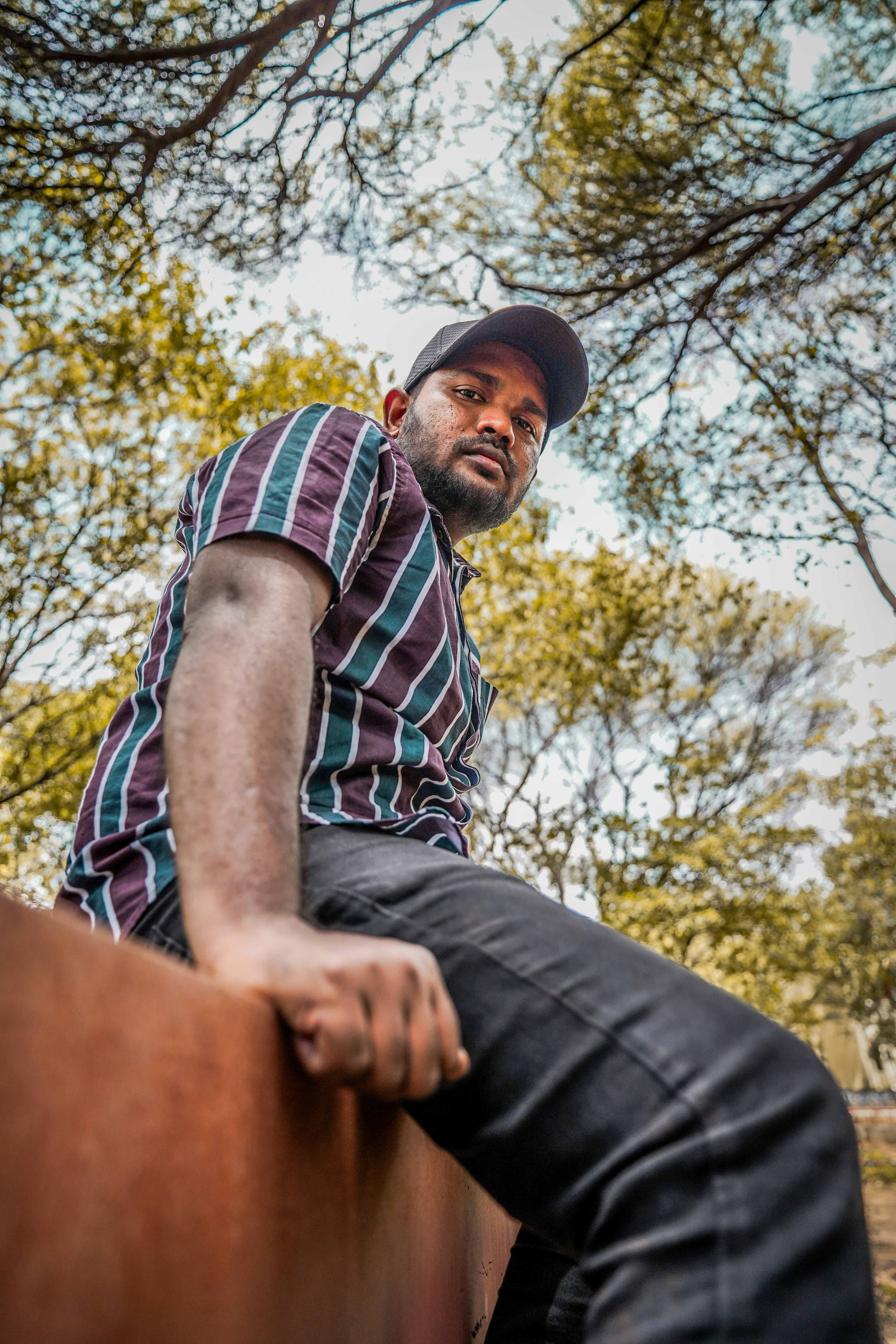 man in blue white and red plaid button up shirt and black denim jeans sitting on on with on with