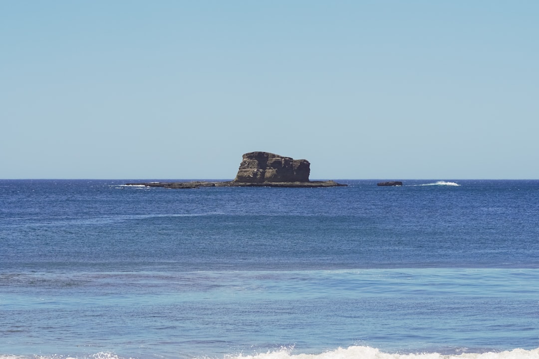 brown rock formation on blue sea under blue sky during daytime