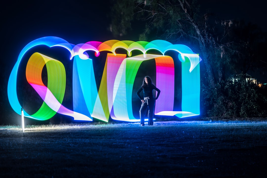 person in black jacket holding rainbow balloons