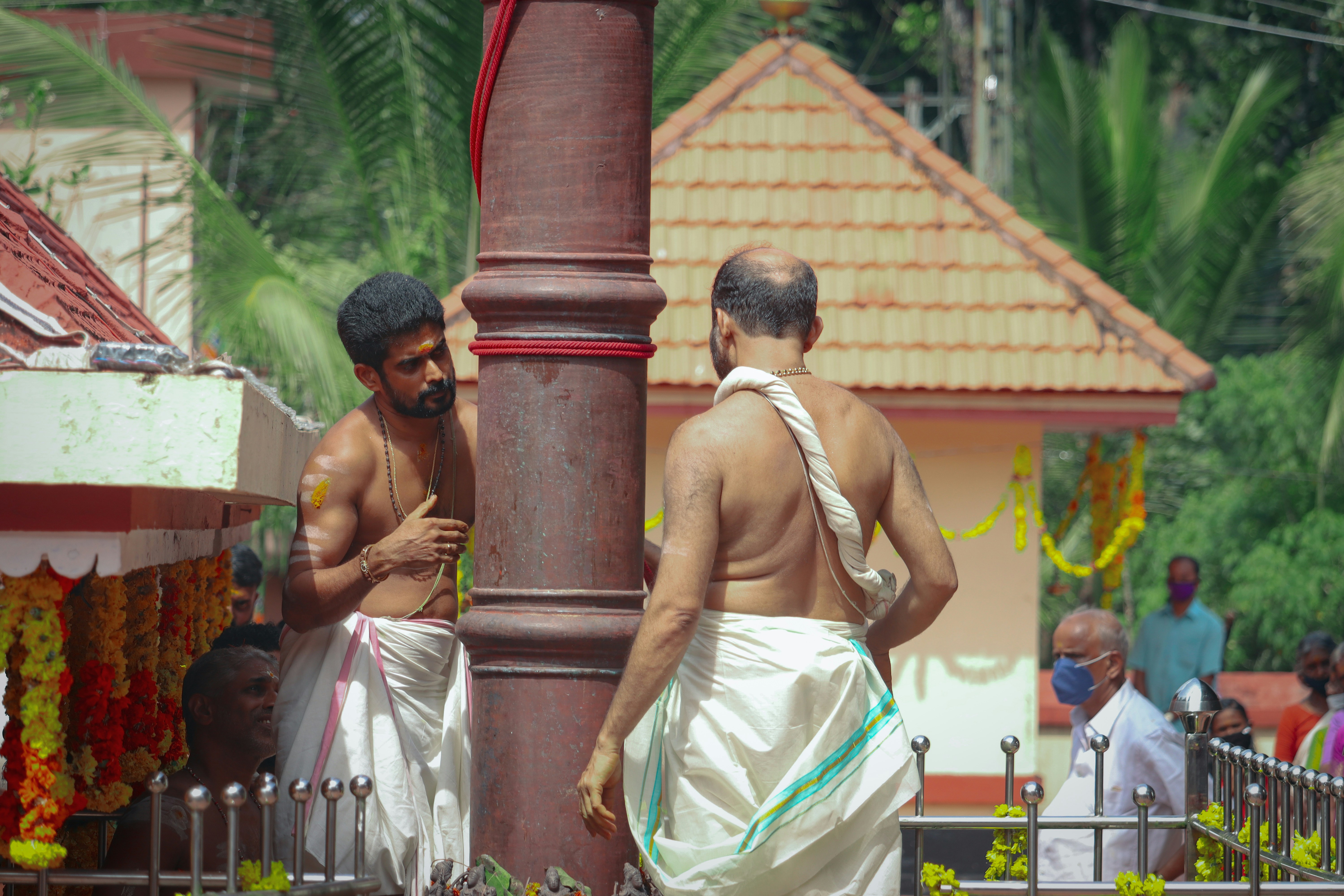 man in white tank top sitting on brown concrete post during daytime