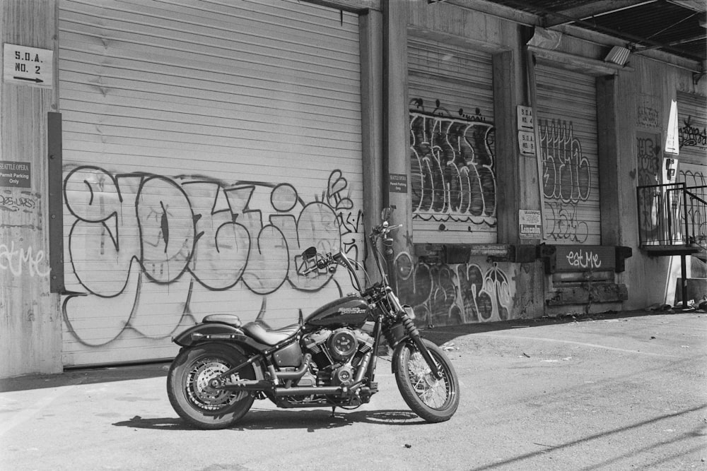 grayscale photo of motorcycle parked beside wall