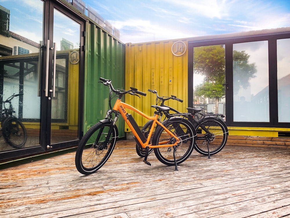 Bicicleta urbana amarilla y negra estacionada junto a una pared de madera marrón