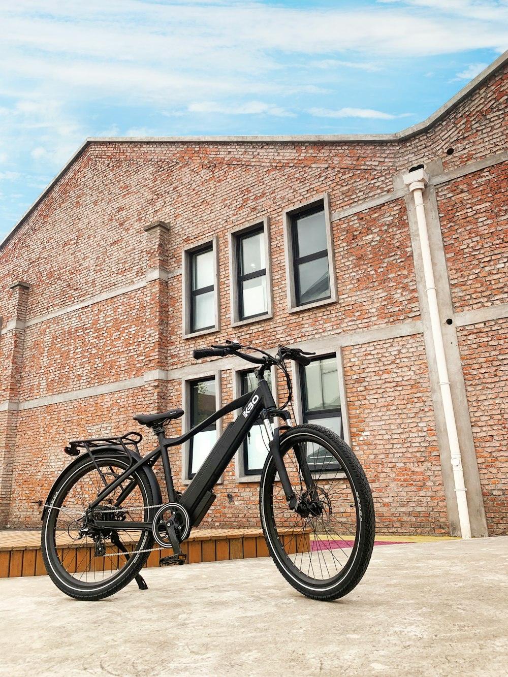 black mountain bike beside brown brick wall