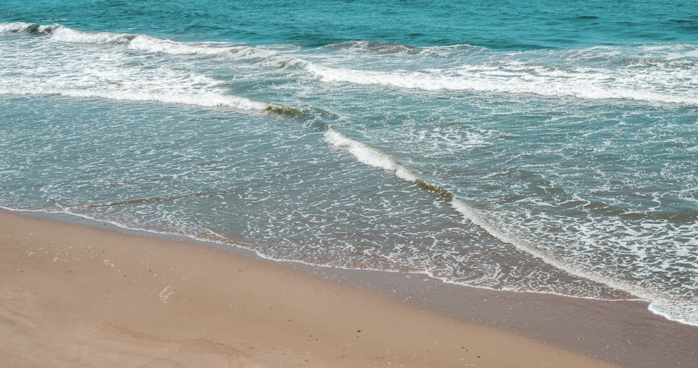 blue ocean waves on brown beach shore during daytime