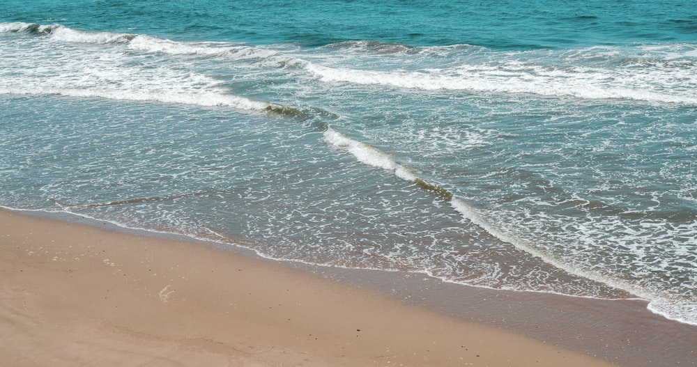 日中の茶色のビーチショアの青い海の波