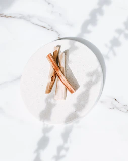 Elegant bamboo dattoon sticks arranged neatly beside a cream-colored ceramic holder on a sand-colored cloth.