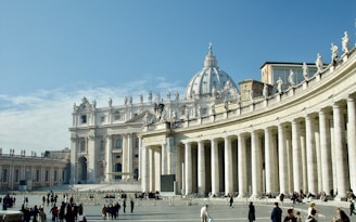 people walking around white concrete building during daytime