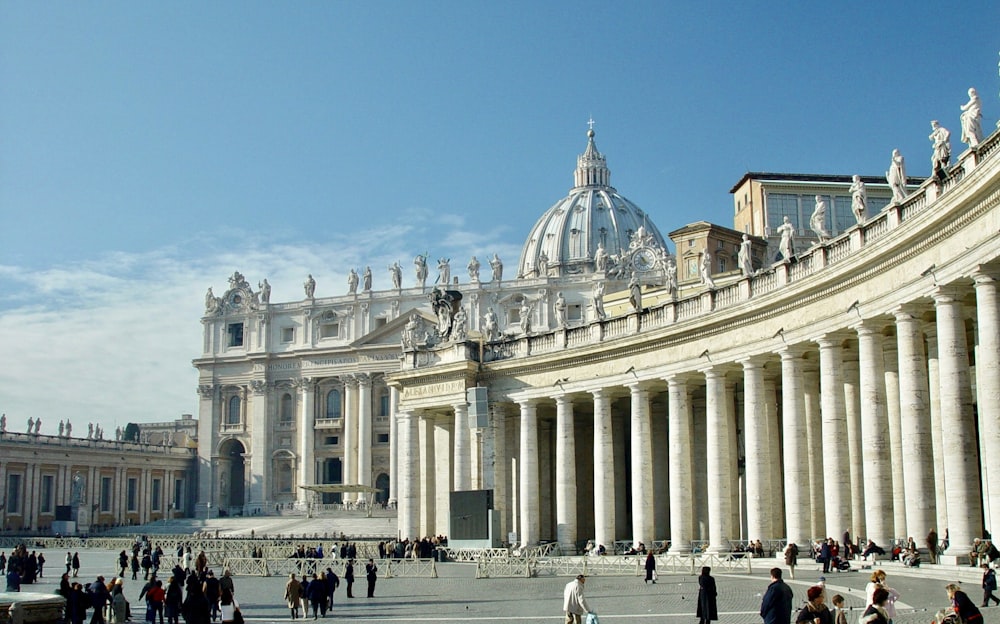 people walking around white concrete building during daytime