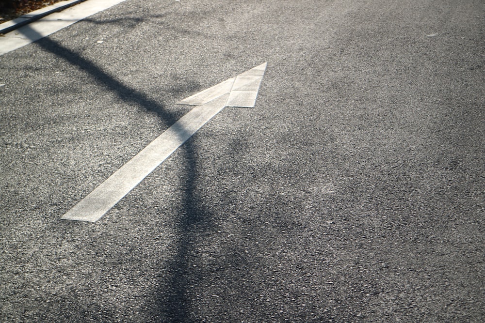 white arrow sign on gray asphalt road