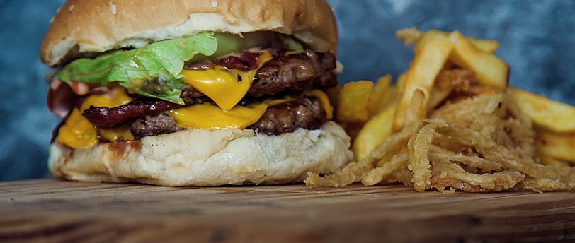 burger with lettuce and fries on brown wooden table