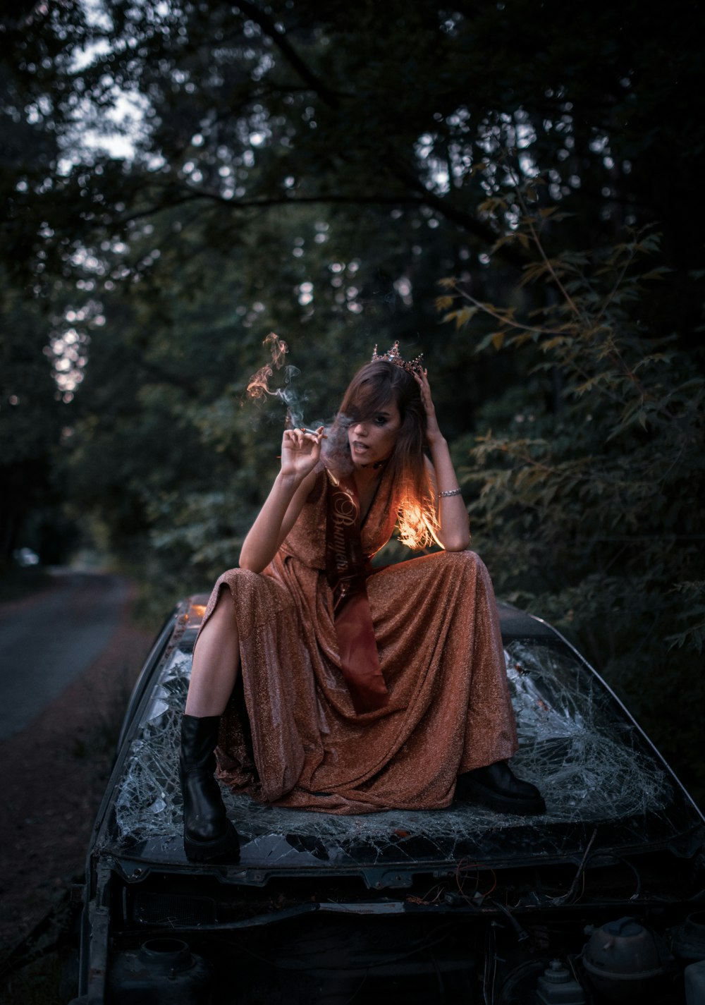 woman in red dress sitting on black car hood during daytime