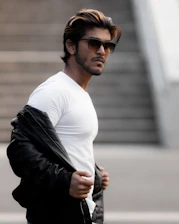 A stylish man confidently wearing a minimalist black t-shirt in a modern urban setting.