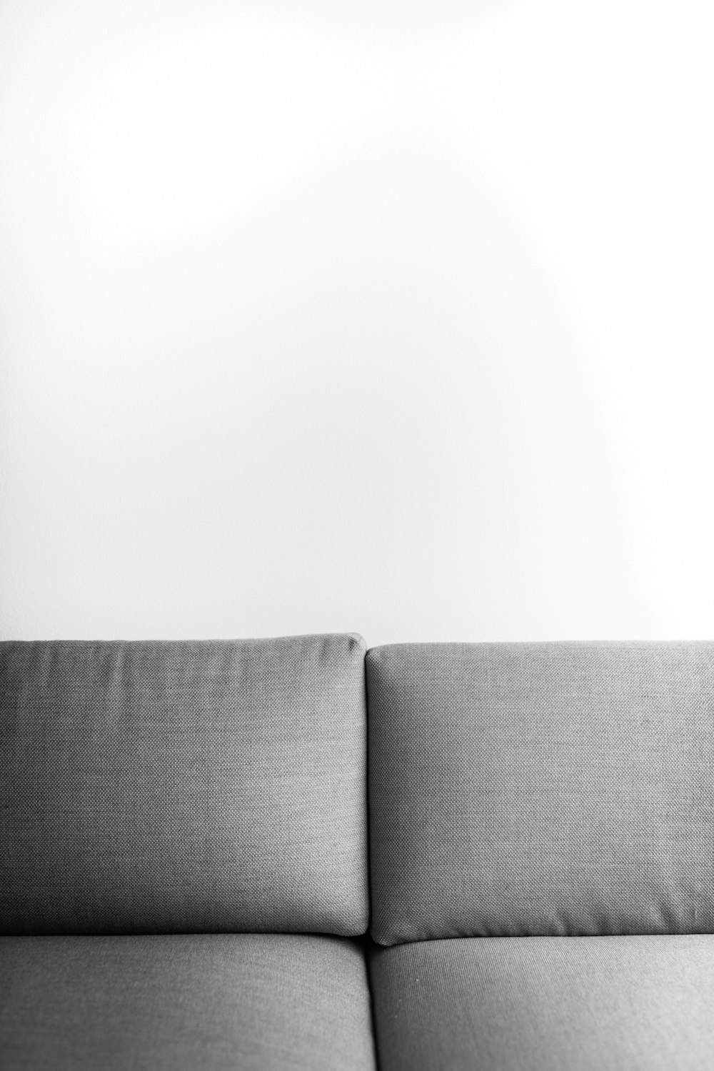 gray cushion couch beside white wall