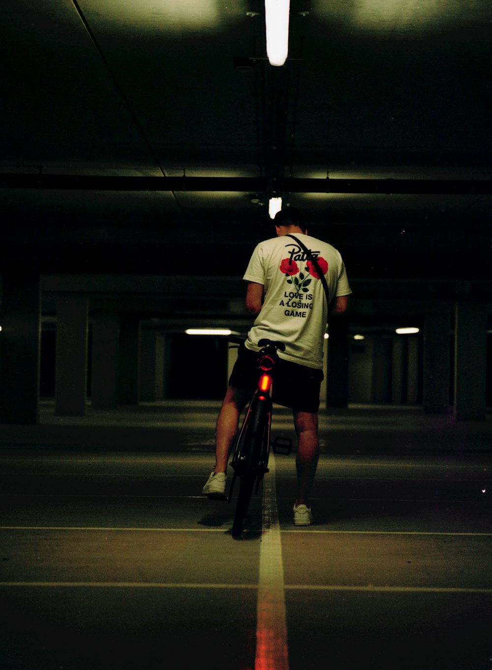 man in white and red crew neck t-shirt and black shorts riding bicycle