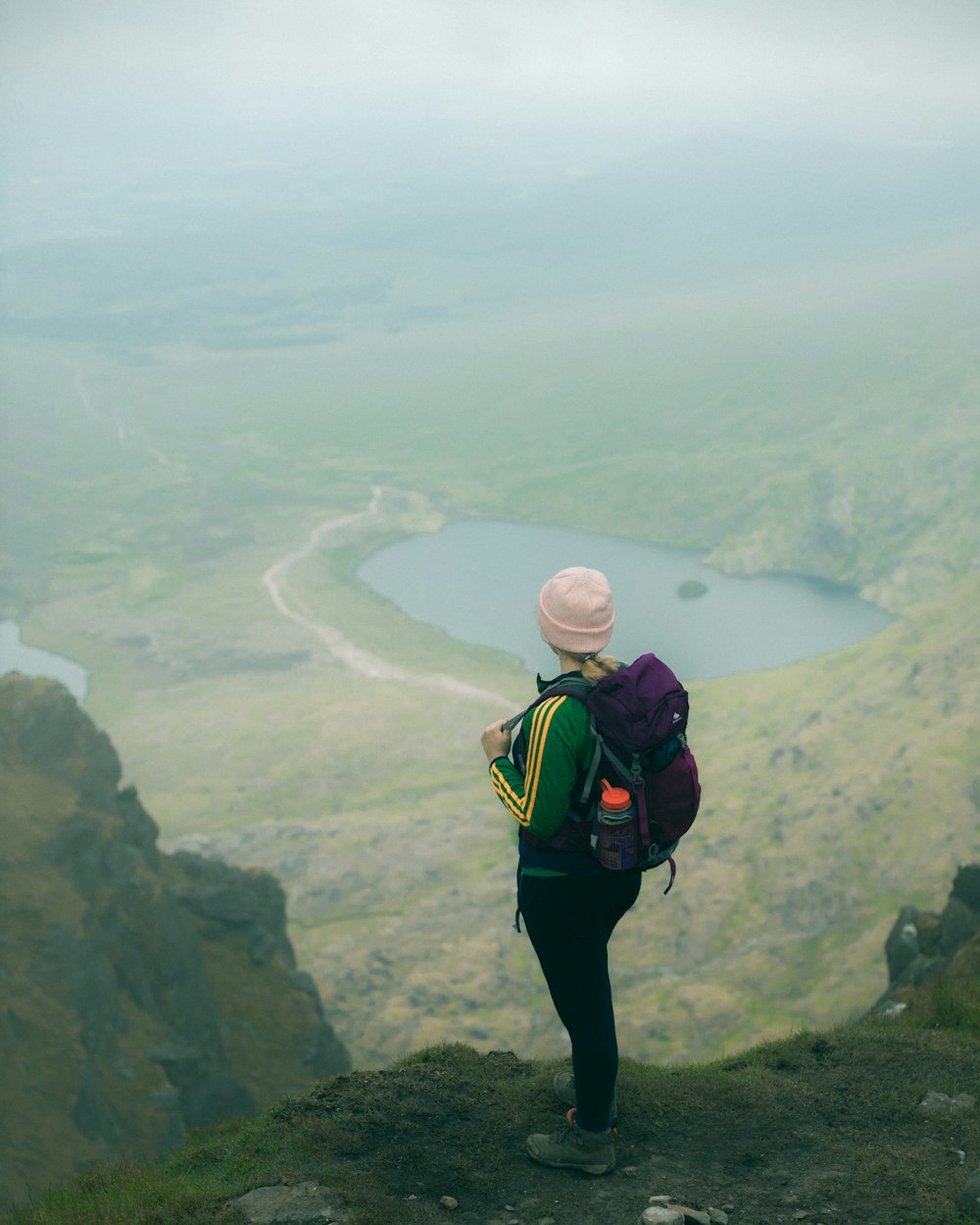 man in black pants and green backpack standing on cliff during daytime