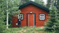 man in black jacket standing beside brown wooden house during daytime