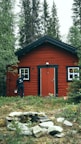 man in black jacket standing beside brown wooden house during daytime