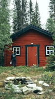 man in black jacket standing beside brown wooden house during daytime