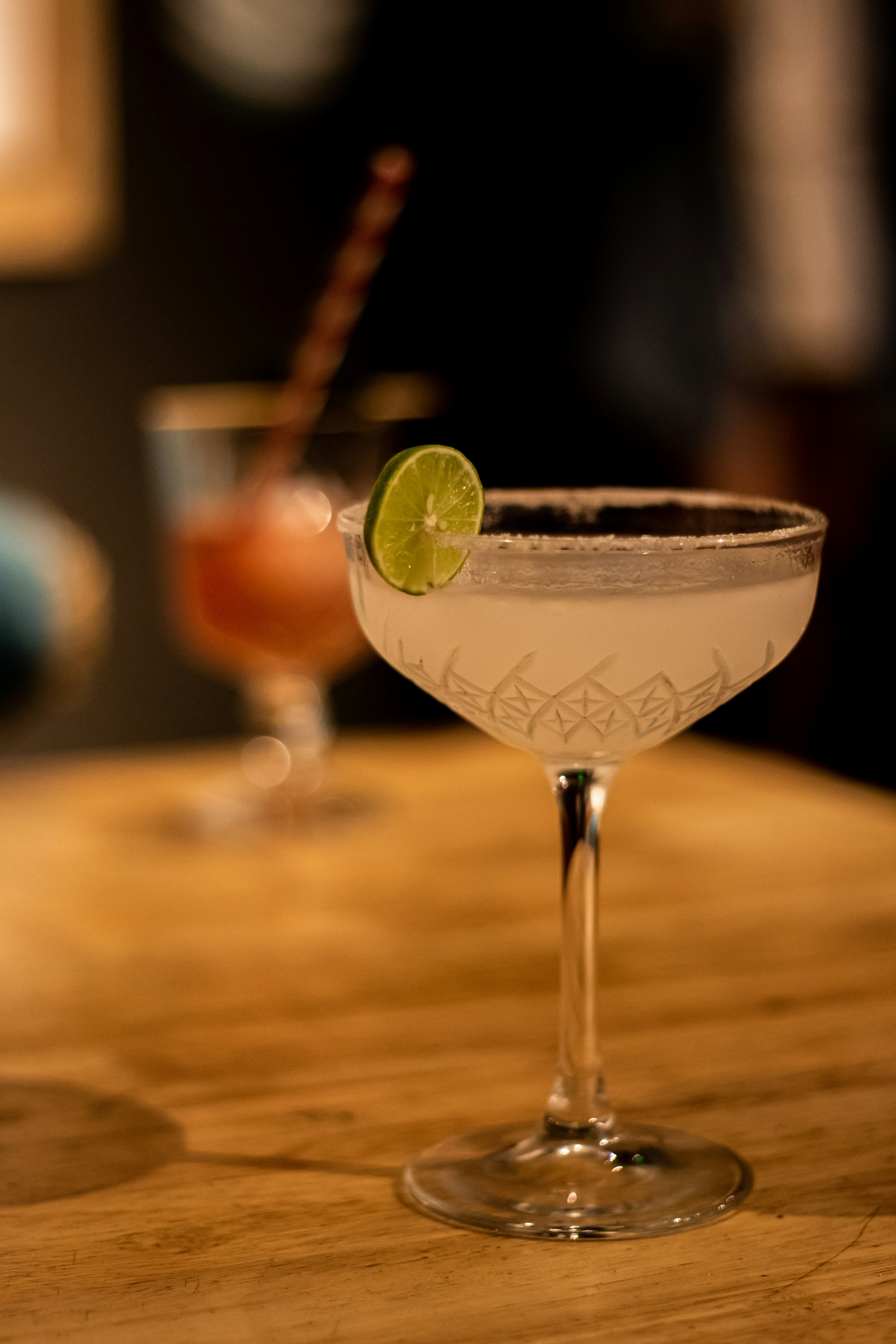 Copa de vino transparente con líquido verde sobre mesa de madera marrón