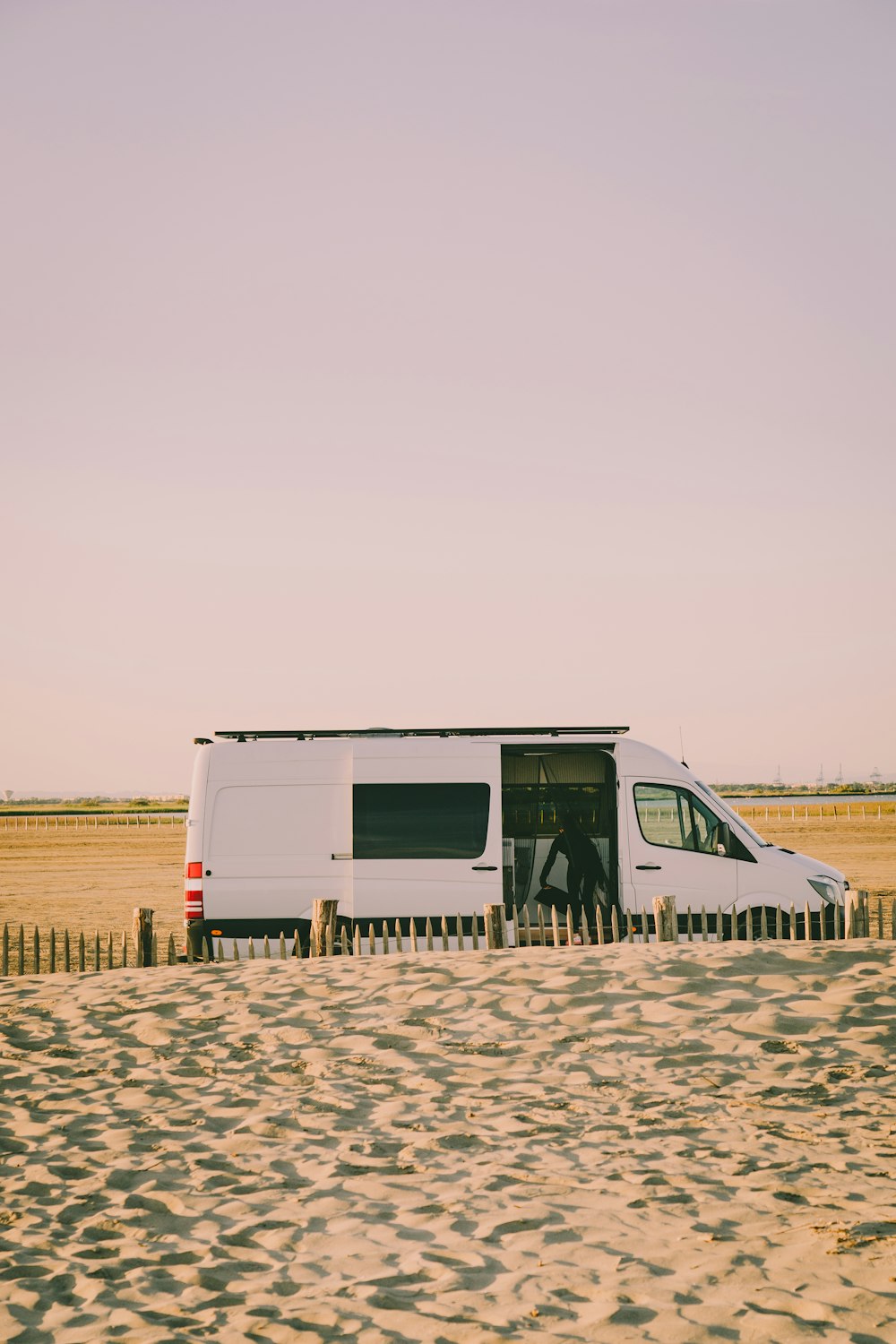 Camping-car blanc et gris sur sable brun pendant la journée