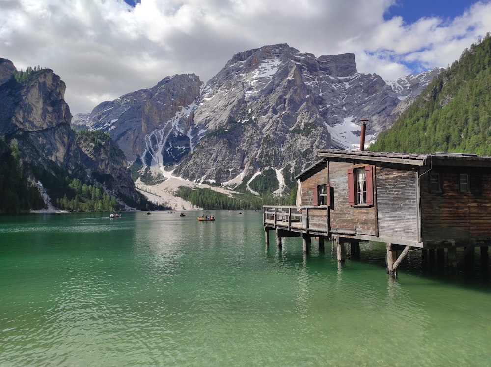brown wooden house on lake near mountain range