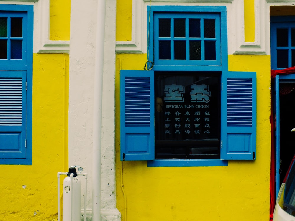 blue wooden window on yellow concrete wall