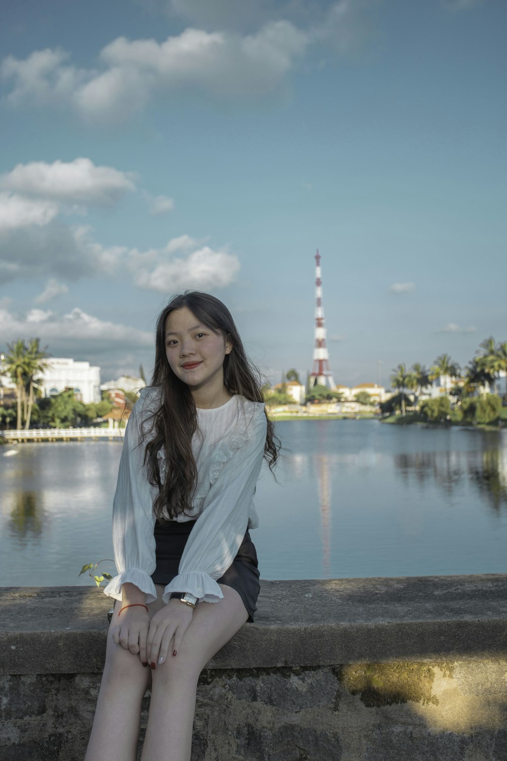 woman in white long sleeve shirt and black pants sitting on brown wooden dock during daytime