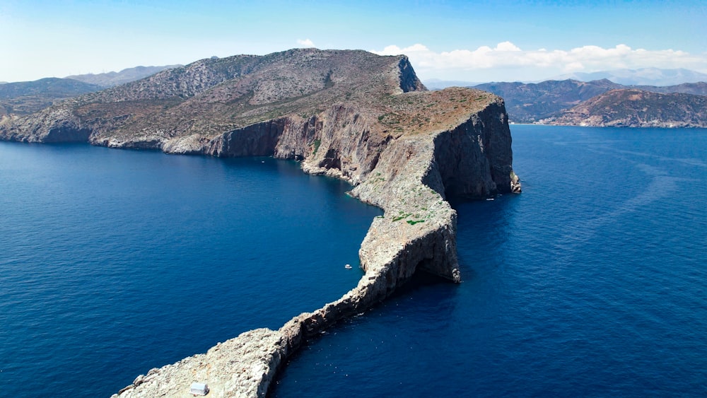 Montagne brune et verte au bord de la mer bleue pendant la journée