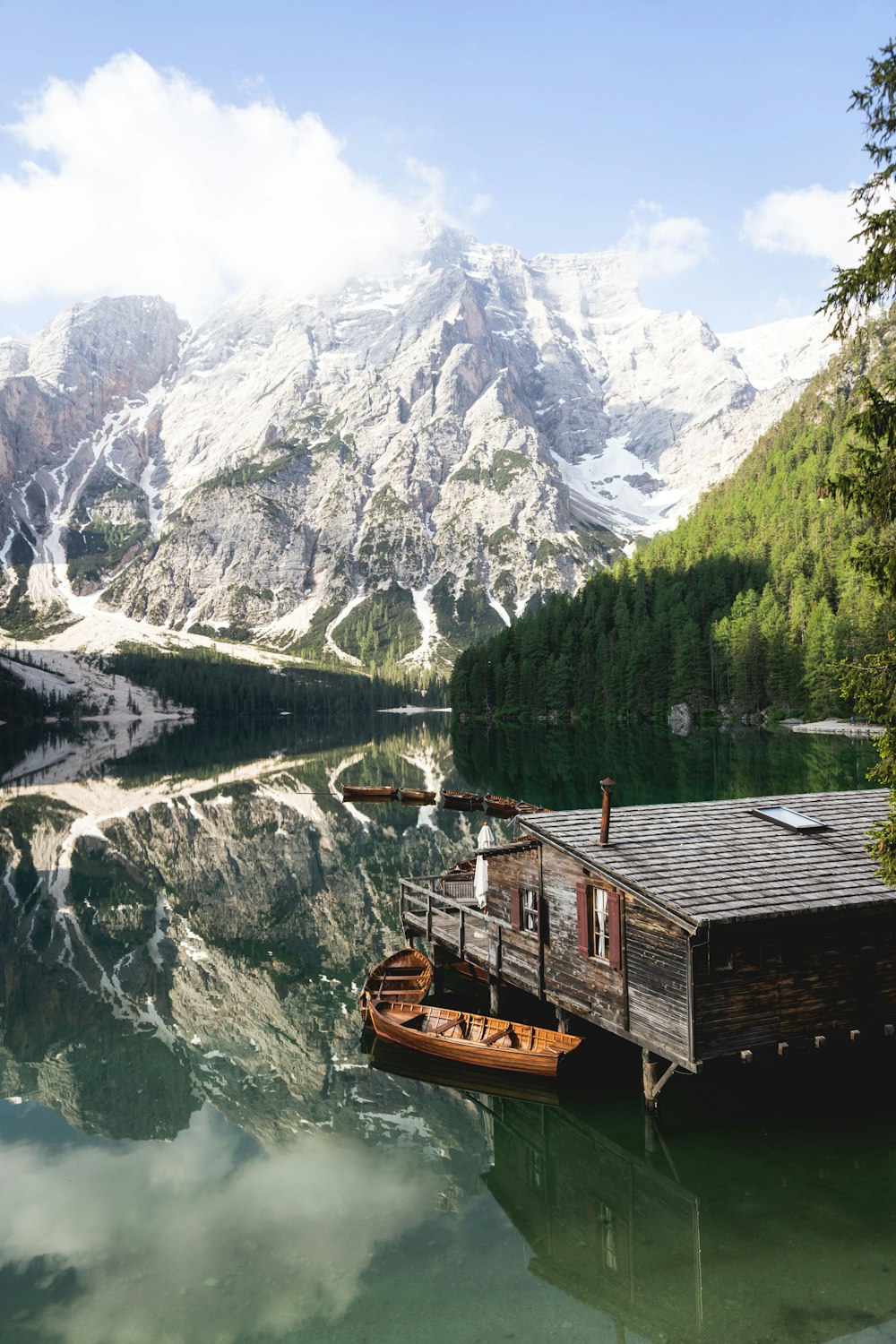 Braunes Holzhaus am See in der Nähe des schneebedeckten Berges tagsüber