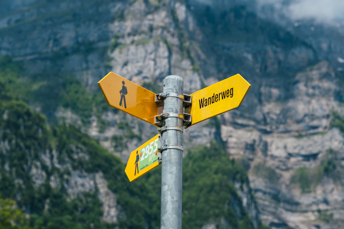 A yellow Swiss hiking signpost in front of a rock face