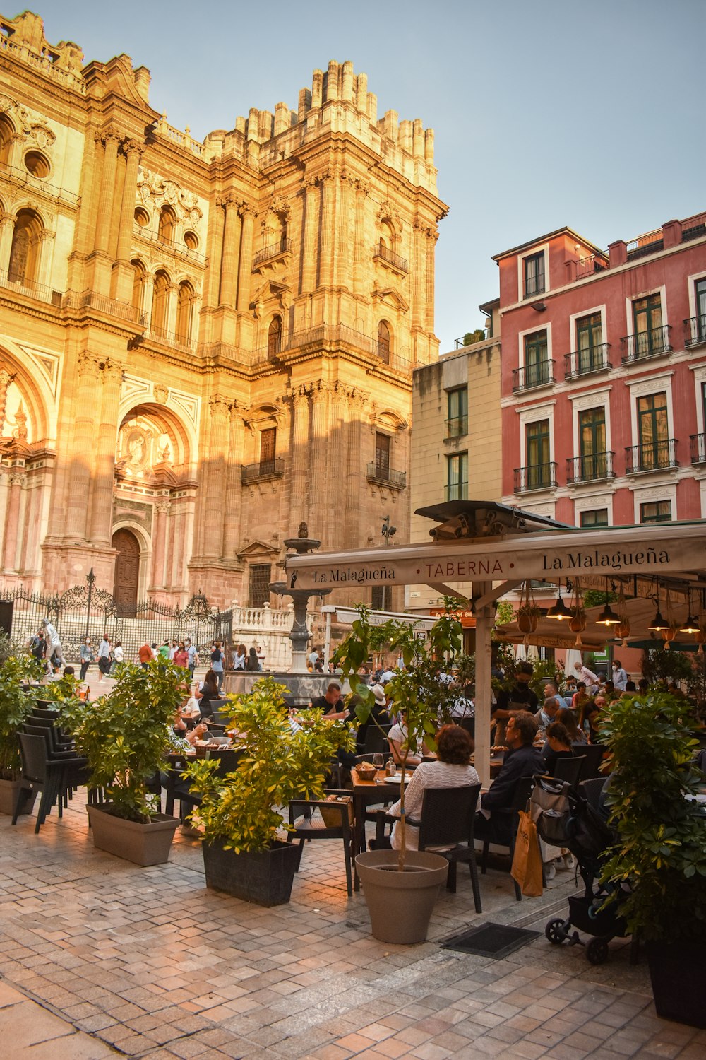 Mensen zittend op een terras voor een kathedraal in Malaga