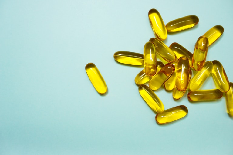 omega-3 yellow supplement tablets on blue background