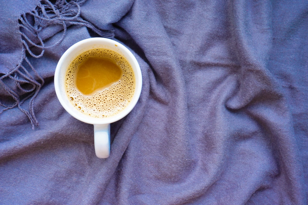 white ceramic mug on gray textile