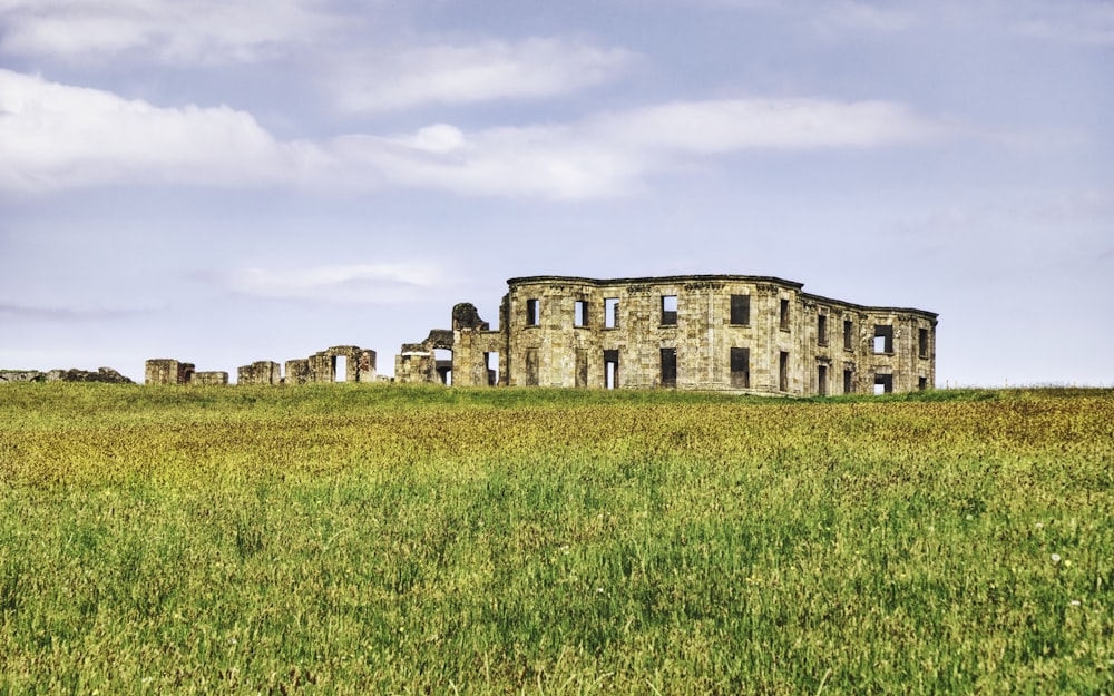 brown concrete building on green grass field under white clouds during daytime