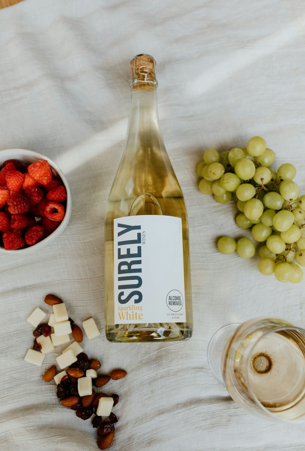 white and red labeled bottle beside white round fruits on clear glass bowl