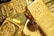 A collection of gold bars and coins, prominently displaying engravings such as '1 KILO Fine Gold 999.9' from Switzerland. The shiny surfaces reflect light, emphasizing the luxury and value associated with precious metals.