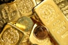 A collection of gold bars and coins, prominently displaying engravings such as '1 KILO Fine Gold 999.9' from Switzerland. The shiny surfaces reflect light, emphasizing the luxury and value associated with precious metals.