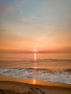 ocean waves crashing on shore during sunset