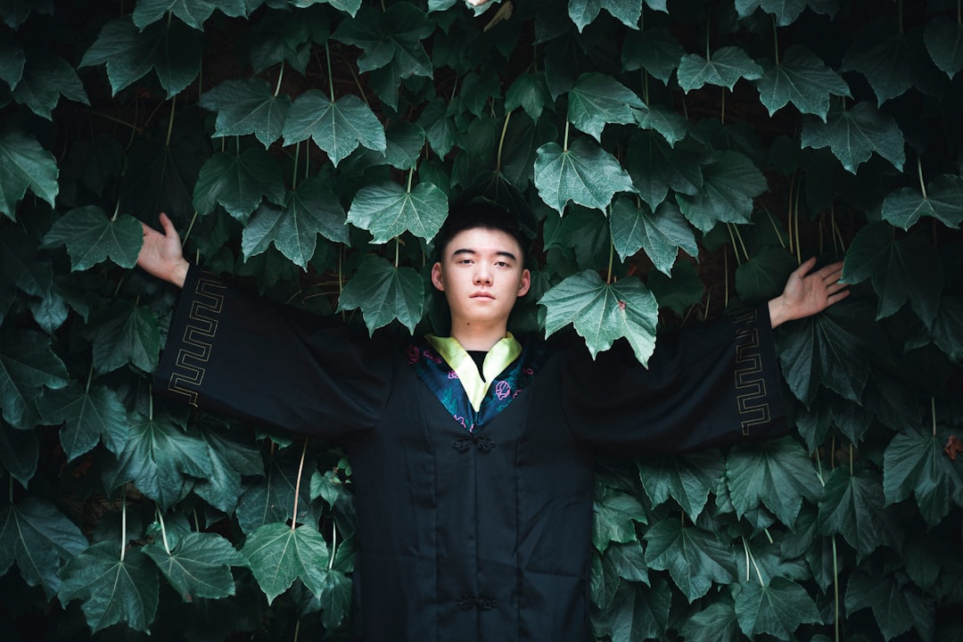 man in black suit standing beside green leaves