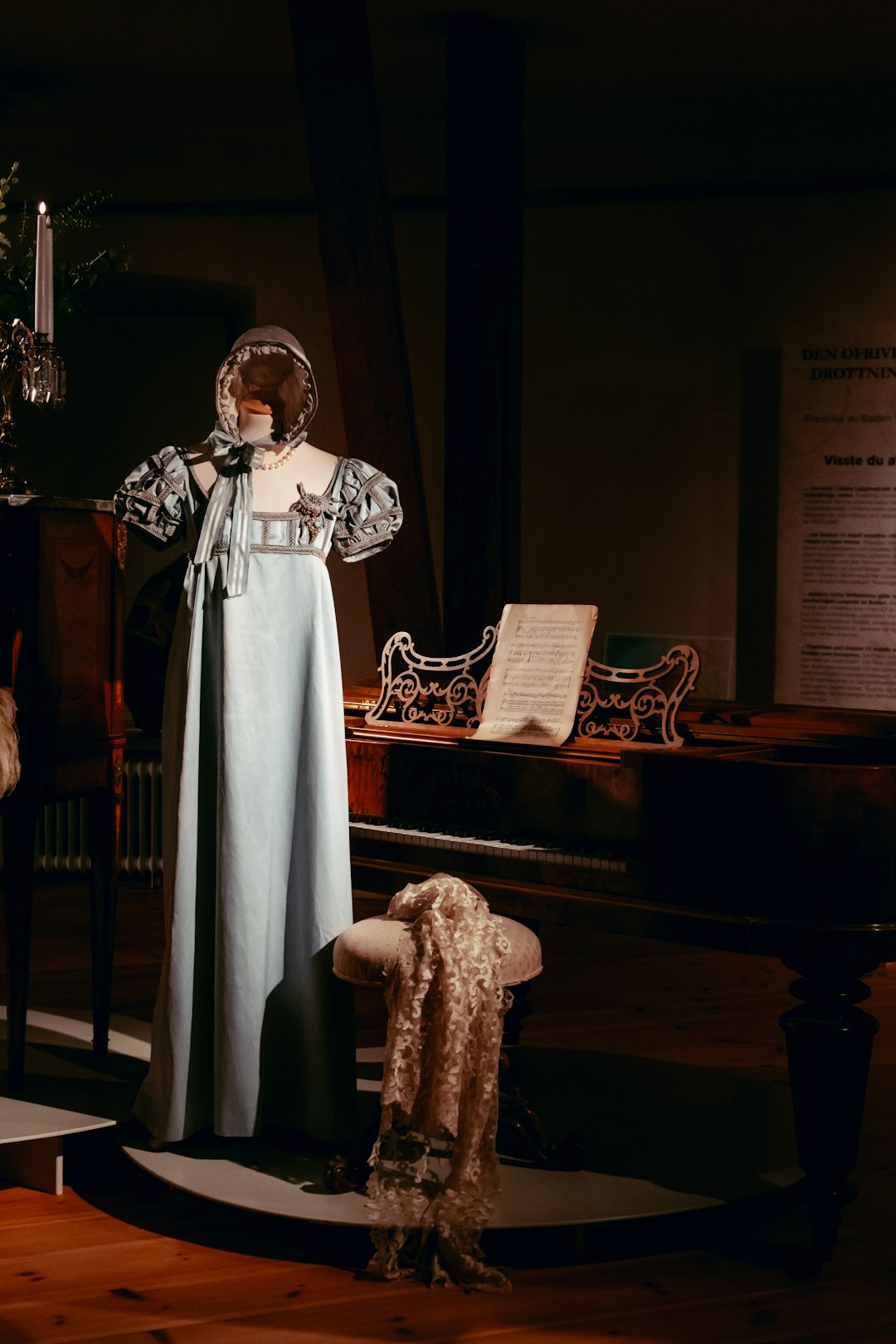 woman in white dress standing beside brown upright piano