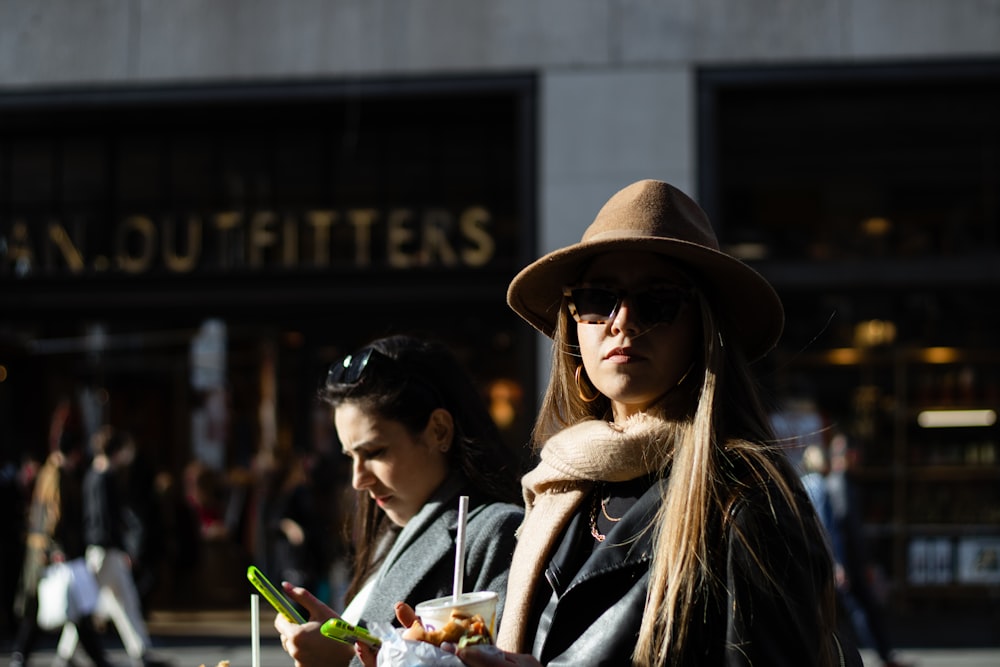 woman in black and white striped long sleeve shirt and brown hat holding green smartphone during