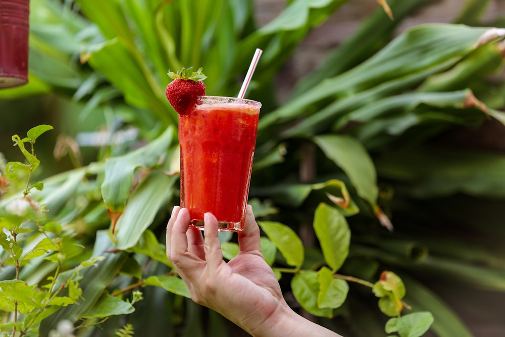 person holding red plastic cup with red liquid